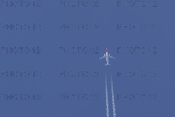 Boeing 737 jet passenger aircraft of Norwegian Air airlines flying in a blue sky with contrails or vapour trails behind, England, United Kingdom