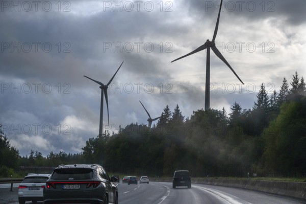 Tourist traffic on the A9 motorway during thunderstorms, wind turbines in the pine forest in the back, Bavarian Forest, Bavaria, Germany