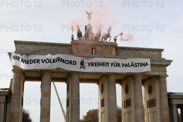 Several activists drop a banner with the inscription Never again genocide, freedom for Palestine and the Palestinian flag and set off pyrotechnics at the Brandenburg Gate, Berlin, 13.11.2025
