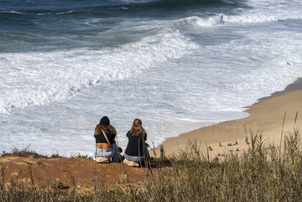 Tourists watch the waves of the Atlantic on the rocky plateau of Sito, also known as Forte São Miguel, a surfing paradise with monster waves in the months of November to February, Nazaré, Portugal