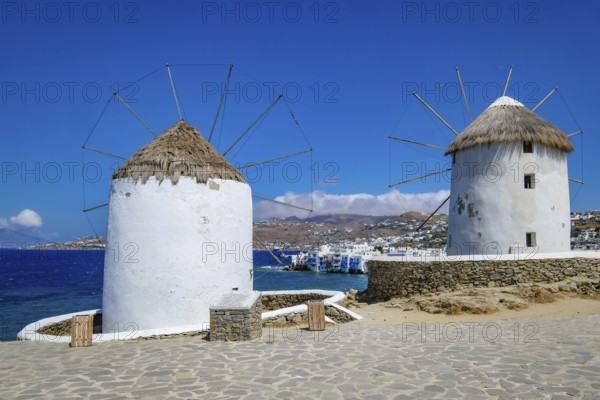 Mykonos, Cyclades, Greece - The six sixteenth-century windmills, lined up on a hill above Mykonos Town, Mykonos Chora, are the island's landmark. At the back, right by the sea, are the colorful houses of Little Venice. Mykonos is part of the Cyclades archipelago in the Aegean Sea