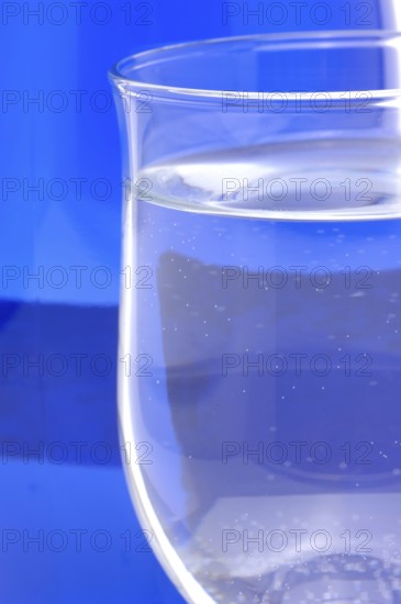 Glass with mineral water, small carbonated pearls on the edge of the glass, drinking water