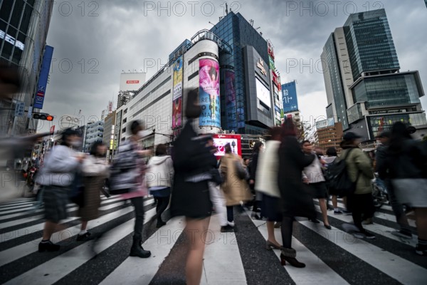 Crowd crossing zebra crossing on a large intersection, motion blur, back modern houses with colorful neon signs, long exposure, Shibuya Crossing, Shibuya, Tokyo, Japan