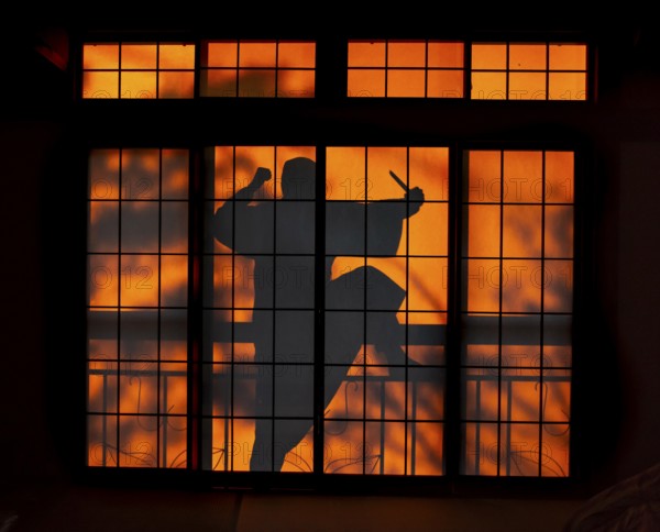 Shadow of a man, burglar with knife, assassin, ninja, on the balcony behind sliding shoji doors in a traditional Japanese house, Yamanouchi, Nagano, Japan