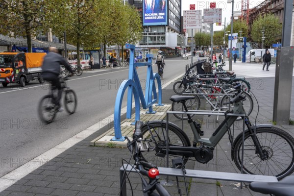 Bicycle parking spaces, with so-called leaning bars and a large blue bicycle silhouette, to make parking spaces visible at Bochum City Hall, North Rhine-Westphalia, Germany