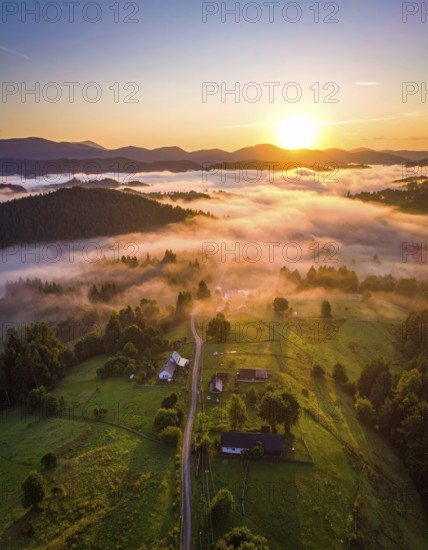 Sunrise over a fog covered village in a rural landscape, golden morning light, serene autumn atmosphere, hills and mountains in the background, AI generated