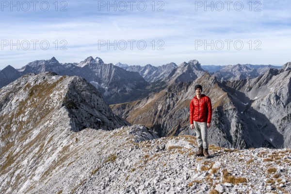 Hikers on the summit ridge of the Gamsjoch, behind rock faces of the Laliderer Spitze, eastern Karwendel, Tyrol, Austria