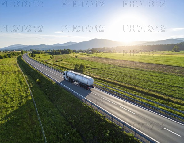 Petrol cargo truck lorry tanker driving on highway hauling oil products at sunrise, wide hilly landscape, AI generated