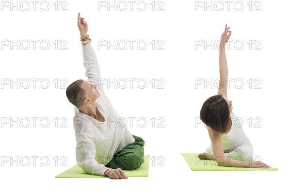 Couple in white sport tshirts and green trousers doing yoga exercises on green mats in studio isolated shot