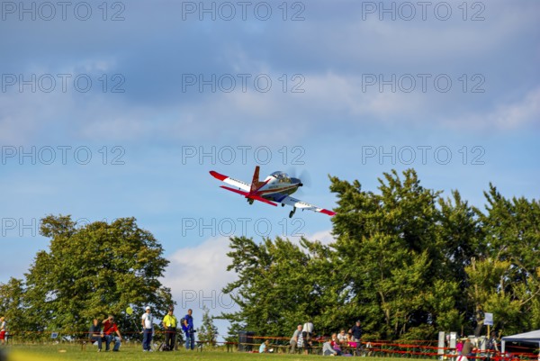An RC model of a Pilatus PC-21 with advertising for the Swiss watch brand Breitling during a flight demonstration as part of an air show at the Rossfeld in Metzingen-Glems, Baden-Württemberg, Germany, for editorial use only