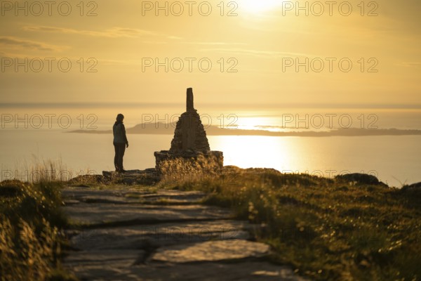 Woman standing next to cairn and looking at the sea, Rørsethornet stone staircase, with 3292 steps one of the longest continuous stone staircases in the world, Sherpat stairs or Midsund stairs or Midsundtrappene, Rørsethornet hike, evening mood, Otroya or Otrøya island, Møre og Romsdal, Norway