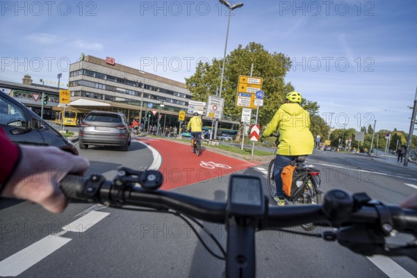Riding a bike in a bike lane, marked in red to attract the attention of motorists, between 2 lanes, Huyssenallee, in front of Europaplatz, in the city centre of Essen, North Rhine-Westphalia, Germany
