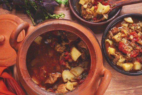 Chanakhi, a Georgian dish. in a clay pot, on a wooden table, stewed meat with vegetables, homemade, no people