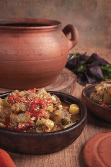 Chanakhi, a Georgian dish. in a clay pot, on a wooden table, stewed meat with vegetables, homemade, no people