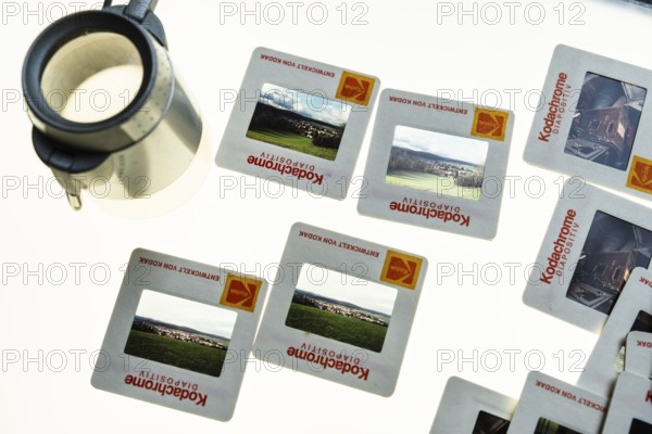 Many framed Kodachrome slides on a light table with magnifying glass, top shot
