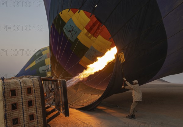 In order to get ready for the take-off, the pilot inflates the balloon with hot air by activating the burner. At dawn. Namib Desert, Kulala Wilderness Reserve, Namibia