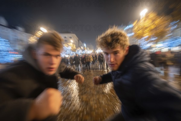 Two men in fighting pose on a rainy street at night, surrounded by lights, symbolic image for physical altercation among youths, use of force, physical violence, act of violence, aggressive behaviour, brawl, AI generated