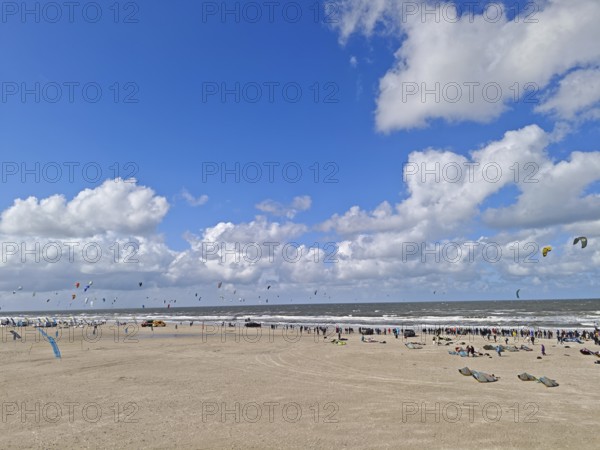California kitesurfing Masters 2025 at the edge of the UNESCO World Heritage Wadden Sea, North Sea, kitesurfing sport, flying kites, spectators, fun, competition, strong wind, whitecaps, beach, summer, sunshine, blue sky, white clouds, Ording, Sankt Peter-Ording, Schleswig-Holstein, Germany