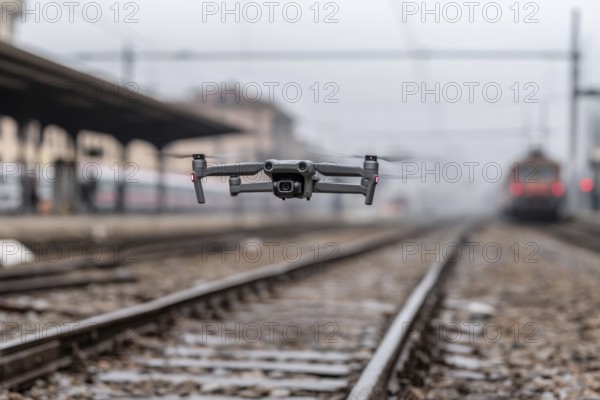 Ein Fernpilot steuert sein Quadrocopter, Drohne illegal über Bahnhofsgelände, Bahngelände, Bahnschienen, Symbolbild für illegaler Drohnenbetrieb über Bahnanlagen, kritische Infrastruktur, Kontrollierter Luftraum, Flugverbot, Betriebsverbot, gefährlicher Eingriff in den Bahnverkehr, AI generiert, AI generated