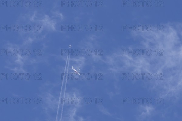 Two airliners Airbus A380 jet passenger aircraft of Emirates airlines and a Boeing 737 of Norweign Air flying in a blue sky, England, United Kingdom