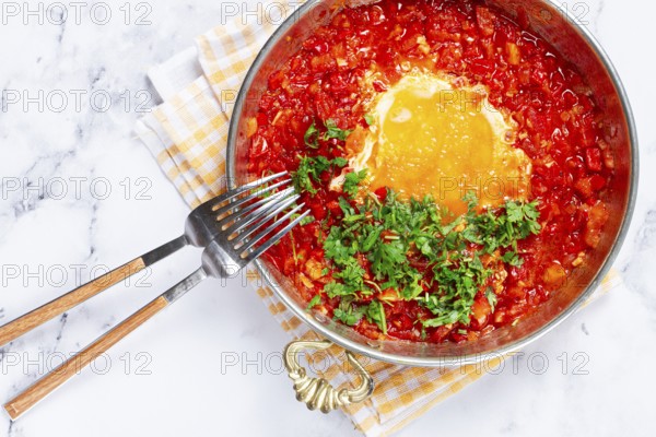 Traditional Turkish dish, scrambled eggs with tomatoes, Menemen, with herbs, in a frying pan, close-up, no people