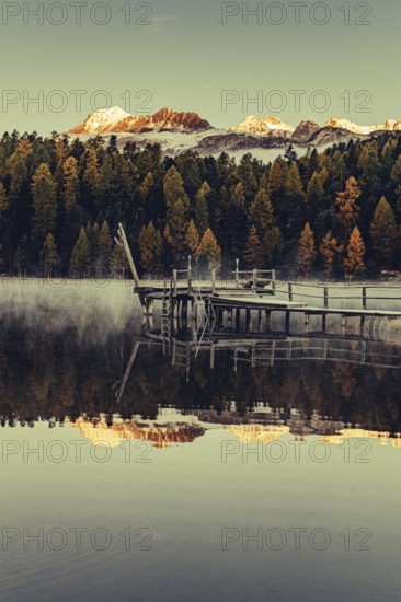 Lake Staz near Sankt Moritz in the Engadin in Switzerland. Morning atmosphere with fog in autumn. Water reflection and snow-covered mountains in the background