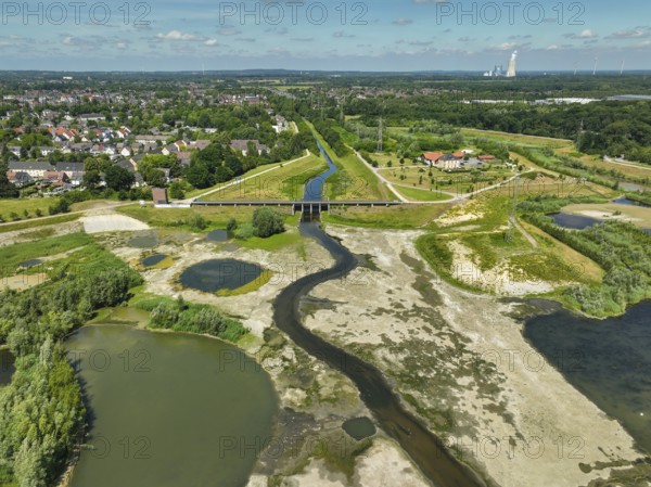 Dortmund, Castrop-Rauxel, North Rhine-Westphalia, Germany - River renaturalisation, renaturation of the Emscher, flood retention basin HRB Mengede. A new floodplain landscape is being created at the Emscher-Auen farm, expanding the area for flood protection during heavy rainfall and for biodiversity. The previously straightened Emscher is being given curves again and can meander through its new floodplain. Following the construction of a parallel sewer, the Emscher has been completely free of sewage since 2022. The river was previously an open, above-ground mixed water channel with rainwater and wastewater. At the back right, the Uniper coal-fired power plant Datteln 4 power station