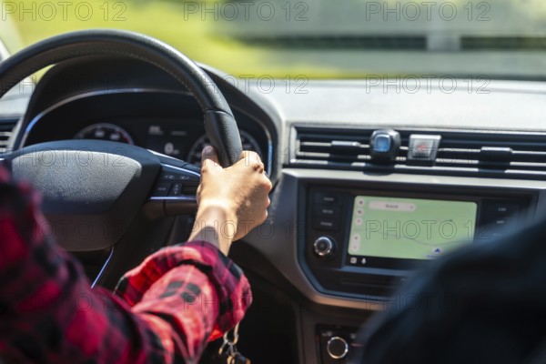 Woman driving a car, holding the steering wheel with left hand and using gps navigation on the dashboard