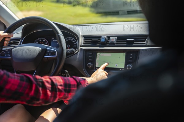 Woman driving a car while interacting with the navigation system on the dashboard's touchscreen display, ensuring accurate route guidance