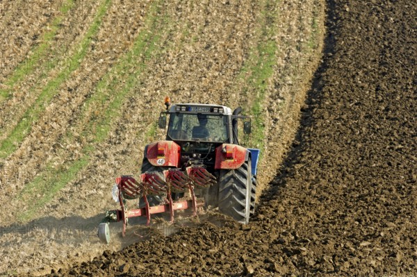 Harvested grain field being turned into a field by Steyr tractor with plough, Hohenpolding, Erding, Upper Bavaria, Bavaria, Germany