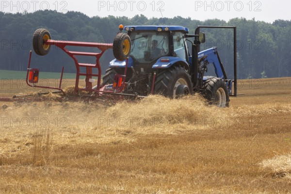 Hastings, Michigan - A farmer uses a New Holland ProTed 3625 tedder to aerate her crop. A tedder spreads out hay or straw to allow quicker drying before baling
