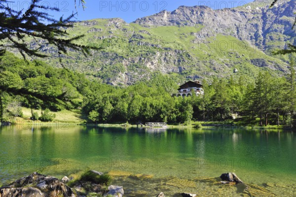 View of mountain lake Lago Grande near Moncenisio in Val Cenischia in the Graian Alps, behind it chalet on the lake, Moncenisio, Piedmont, Italy