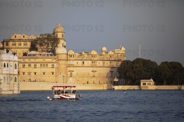 Excursion boat on Lake Pichola, behind the City Palace in the evening light, Udaipur, Rajasthan, India