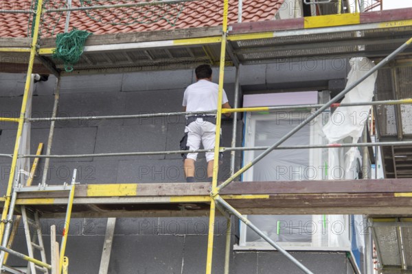 Construction workers insulate a house facade