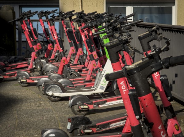 Many rental e-scooters parked on a pavement in Wuppertal, Germany