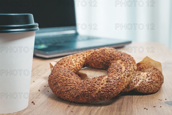 Simits with coffee on a wooden table, with a laptop, in a cozy working environment, snack, breakfast, no people