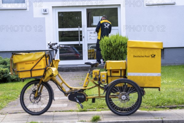 Postman, Deutsche Post, distributes the mail in an apartment building, electric tricycle, North Rhine-Westphalia, Germany