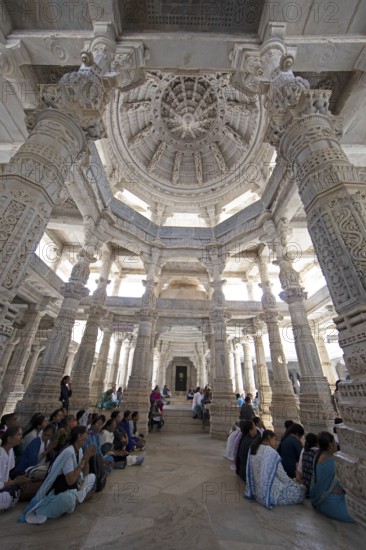 Indian woman praying between the white marble pillars in the Adinath temple in Ranakpur, Jain temple, Rajasthan, India