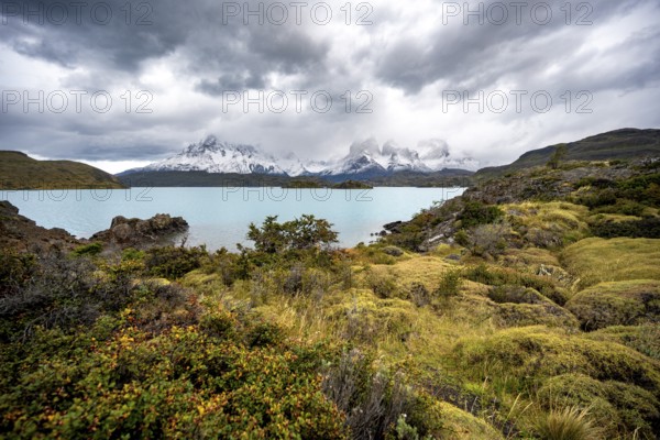 Cloudy mountain range Cuernos del Paine, shore of the blue lake Lago Pehoe in the evening light, dramatic sky, Torres del Paine National Park, Chile