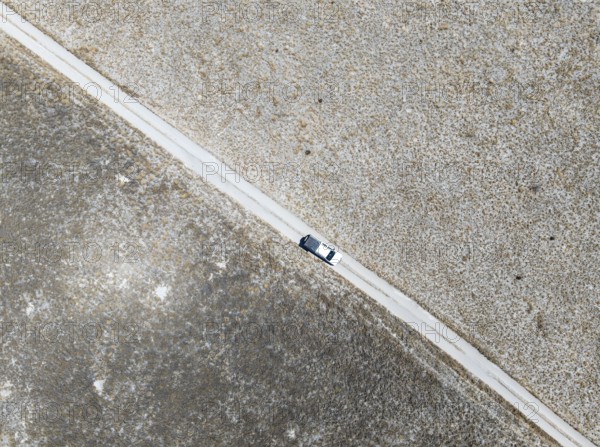 Off-road vehicle driving on a sandy track through a vast dry landscape with yellow grass, Top Down, Sowa Pan, Makgadikgadi salt pans, Botswana