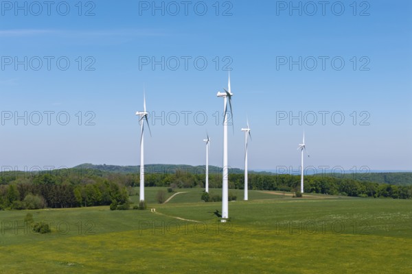 Wind turbines on a green field surrounded by forest under a blue sky, Swabian Alb, Baden-Württemberg, Germany