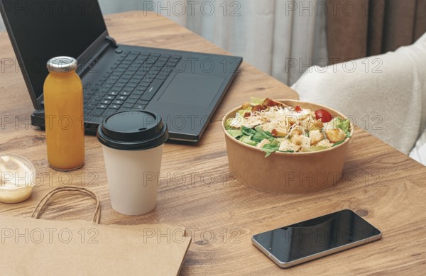 Work at home on a laptop, there is food on the table, salad, coffee and juice, delivery, there are no people