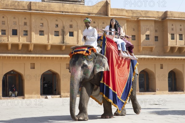 Indian mahout and Indian woman riding a colourfully painted elephant at the Amber Fort or fortress, Jaipur, Rajasthan, India