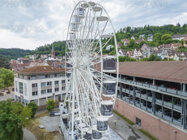 A large Ferris wheel in the middle of an urban environment with a cloudy sky, Ferris wheel construction for the 950th anniversary of the city of Calw, Black Forest, Germany