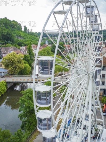 A Ferris wheel near a river, surrounded by trees and buildings, Ferris wheel construction for the 950th anniversary of the town of Calw, Black Forest, Germany