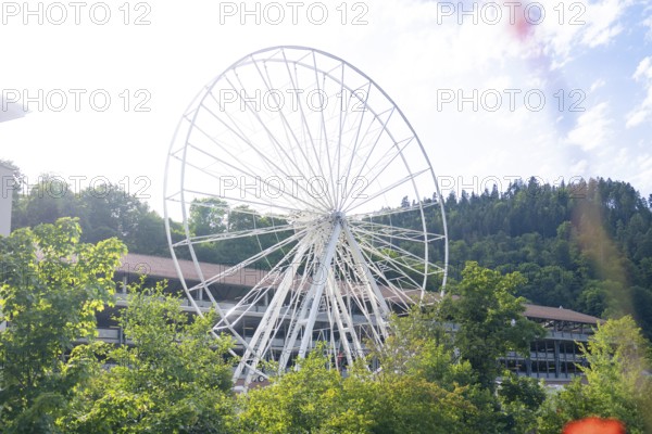 Large white Ferris wheel in front of a building and wooded hills, Ferris wheel construction for the 950th anniversary of the town of Calw, Black Forest, Germany
