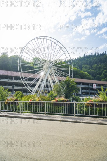 A partially erected Ferris wheel in front of a green forest backdrop on a clear summer day, Ferris wheel construction for the 950th anniversary of the town of Calw, Black Forest, Germany