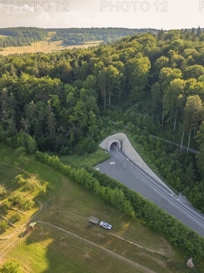 A bird's eye view of a railway tunnel in the middle of a wooded hill at sunset, construction of the Hermann Hesse Railway, Calw, Germany