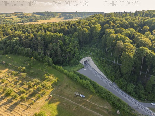 Aerial view of a railway tunnel in the middle of a dense forest and bordering agricultural fields, construction of the Hermann Hesse Railway, Calw, Germany