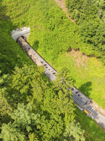 A train disappears into a tunnel, surrounded by forest in a bird's eye view, construction of the Hermann Hesse railway, Calw, Germany